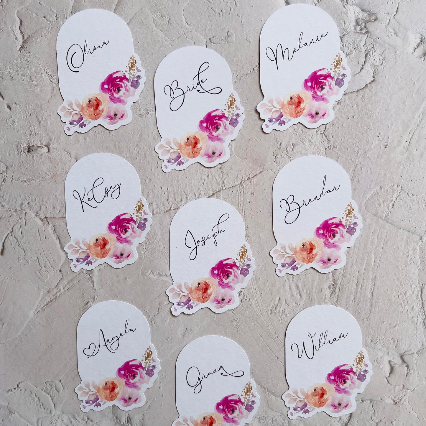 Set of name tags with floral designs on a textured surface