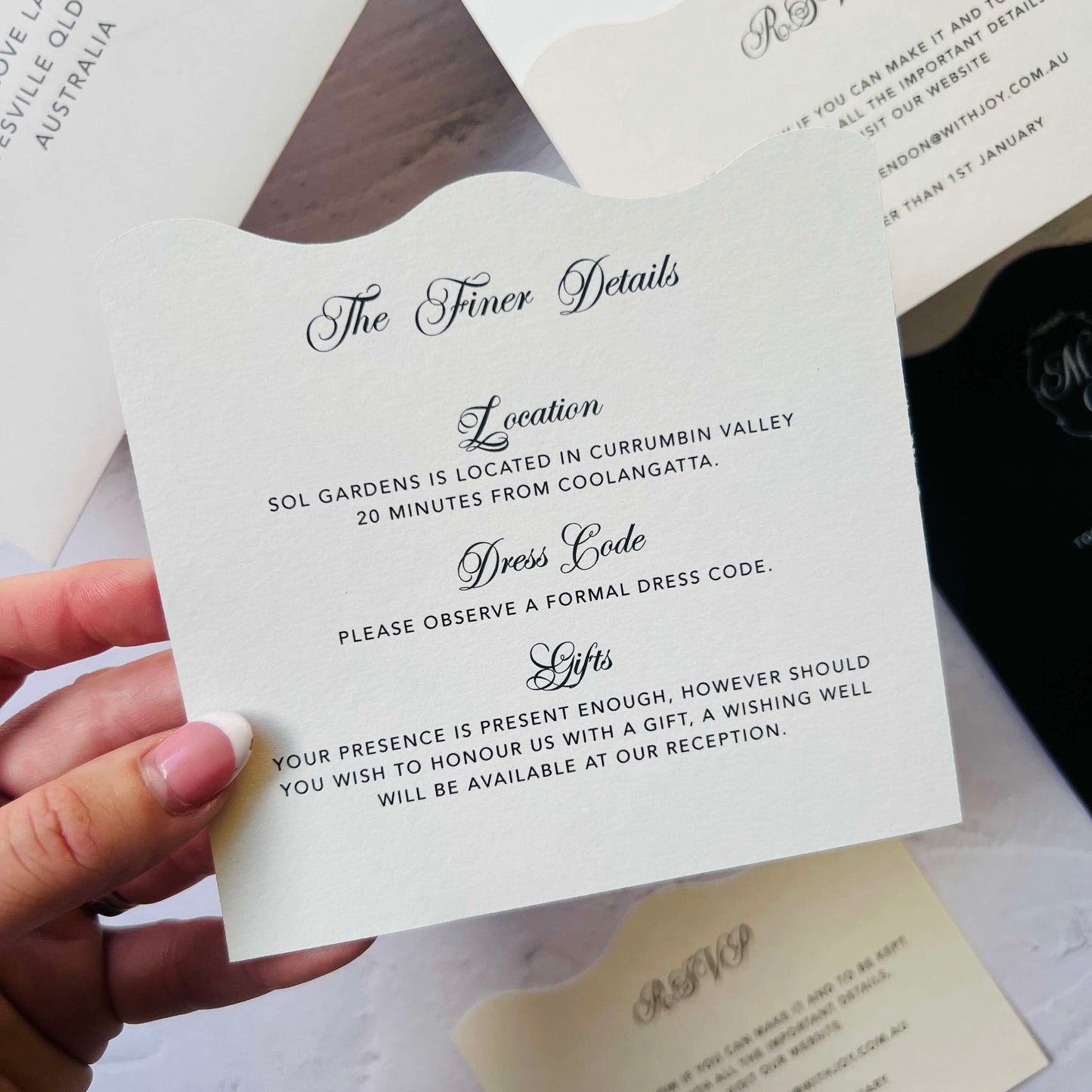 Hand holding a wedding invitation card with text details.