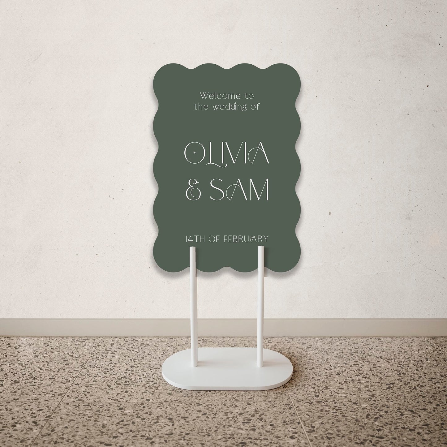 Green Wave Shape Wedding Welcome Sign on a stand against a plain wall