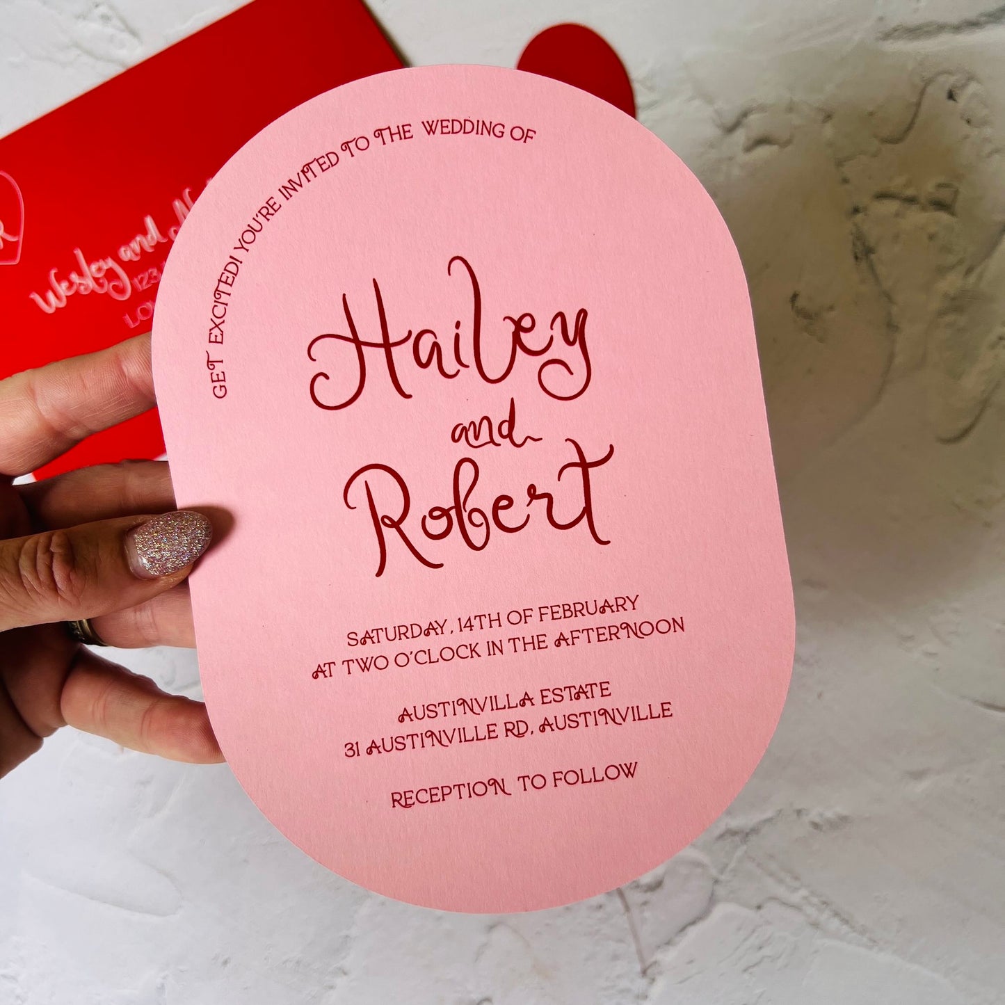 Pink wedding invitation card held by a hand 