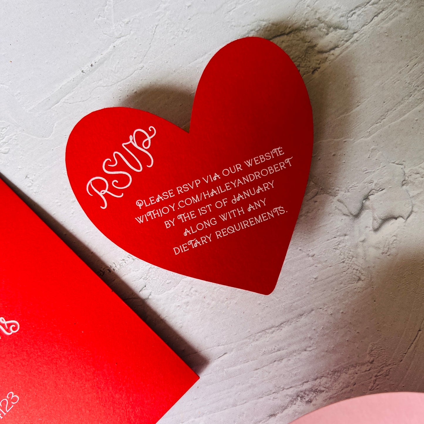 Red heart-shaped RSVP card on a textured white surface