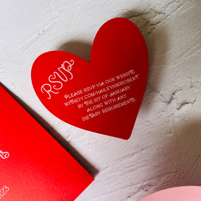 Red heart-shaped RSVP card on a textured white surface