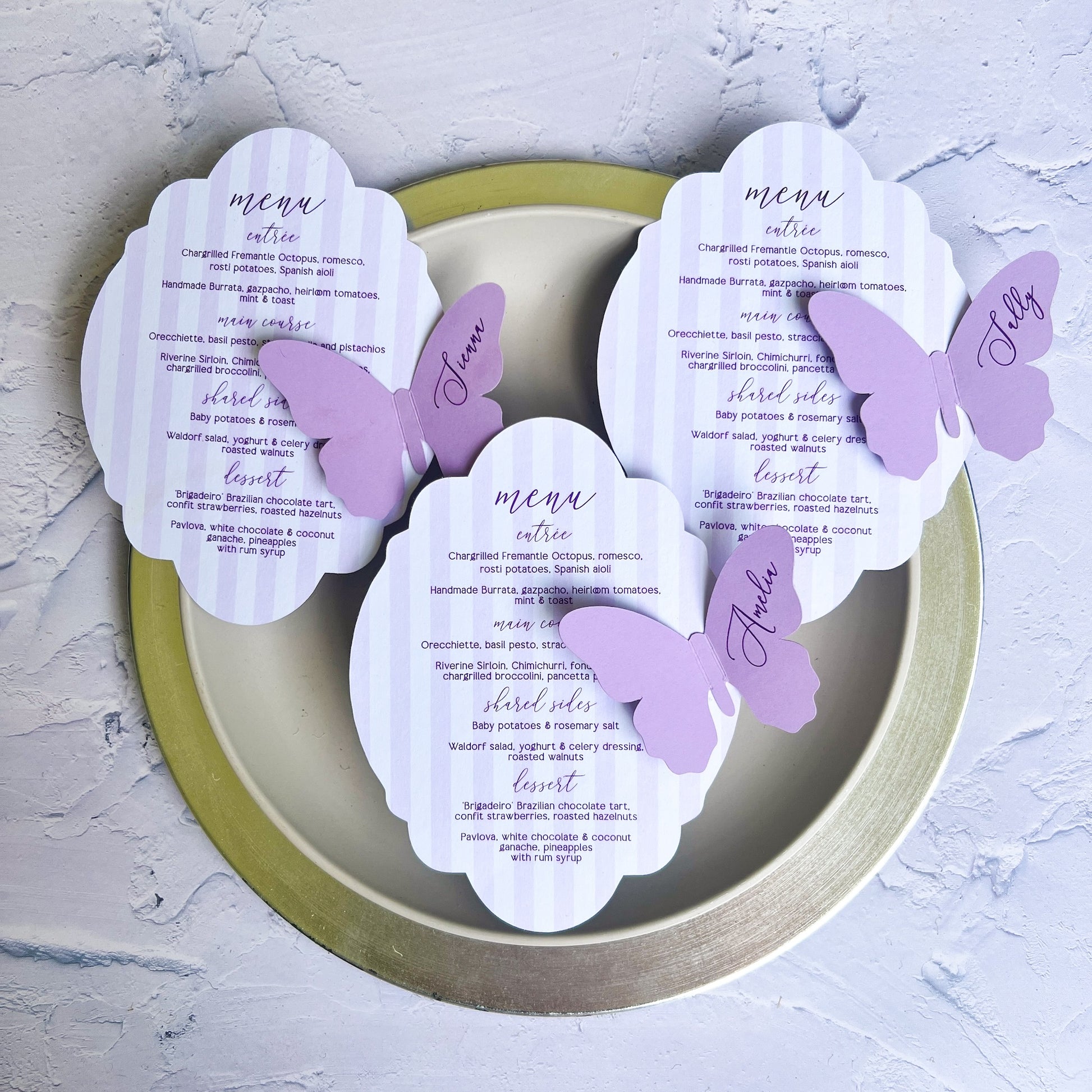 Butterfly-themed menu cards on a decorative plate with a light gray background