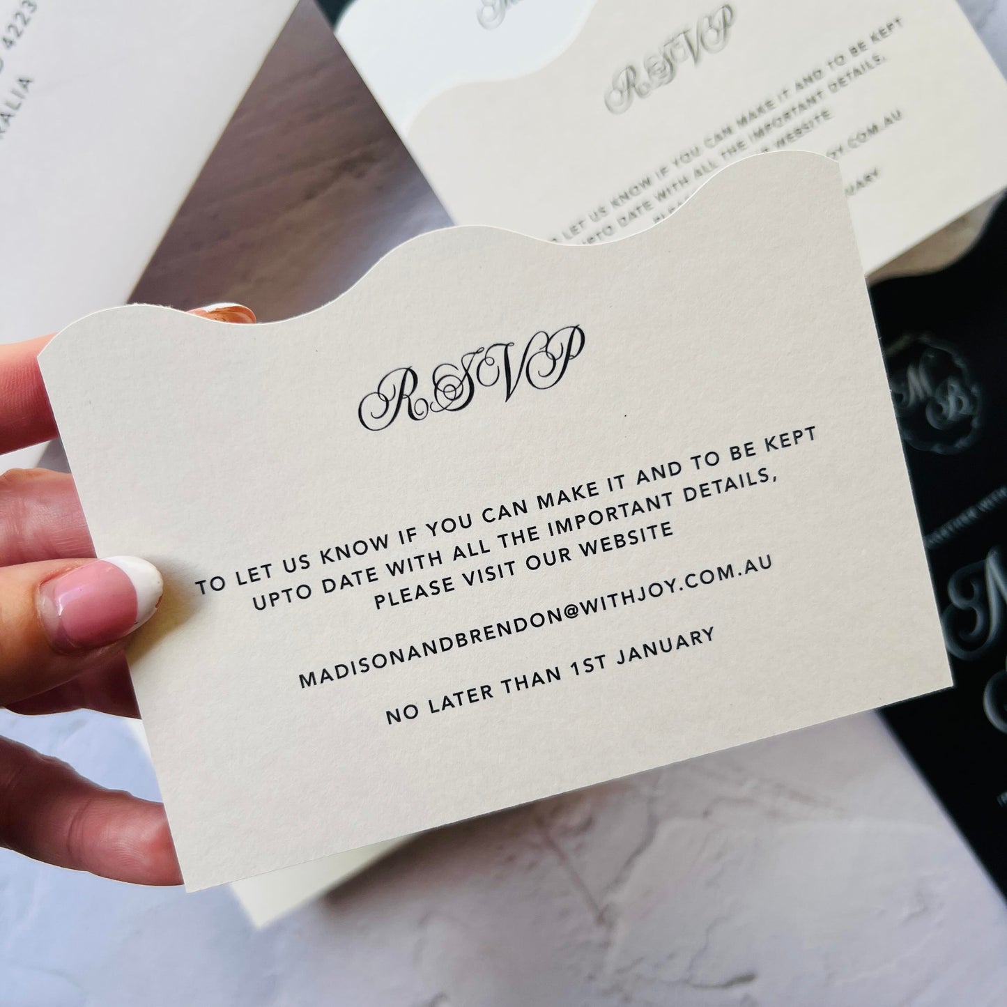 Hand holding an RSVP card with wedding details