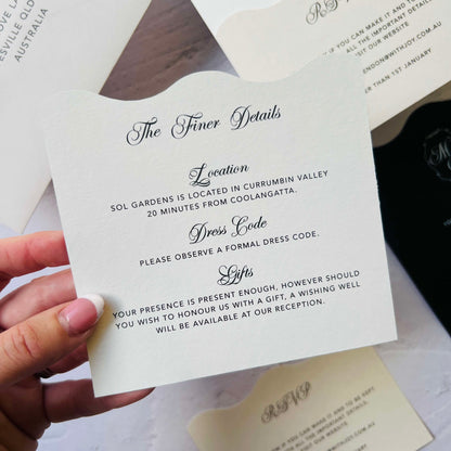 Hand holding a wedding invitation card with text details.