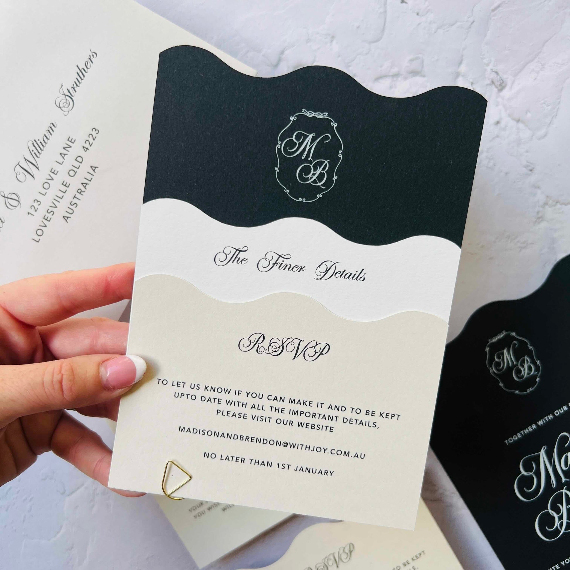 Hand holding a wedding invitation with black and white design