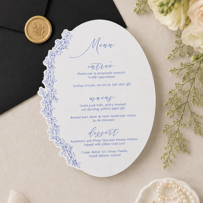 Elegant wedding menu card with floral design on a beige surface with flowers and bow accents.