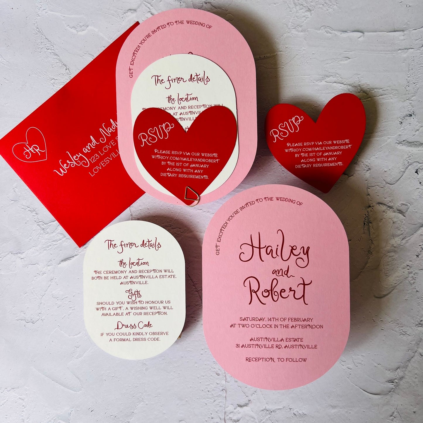 Set of wedding invitations with heart-shaped RSVP cards on a textured surface