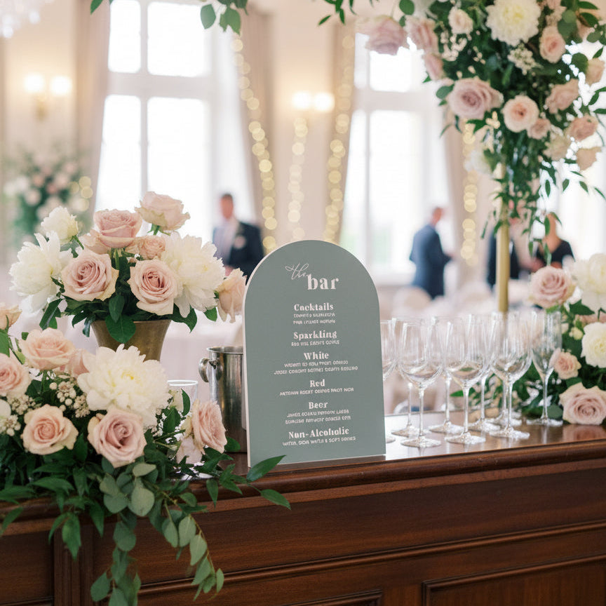 Decorative floral arch with a 'bar' sign on a wooden counter.