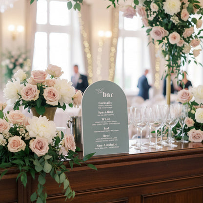 Decorative floral arch with a 'bar' sign on a wooden counter.