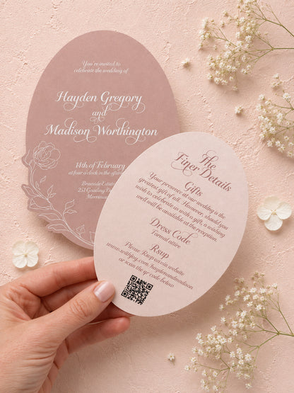 Wedding invitation card with QR code held by a hand on a pink background with flowers.